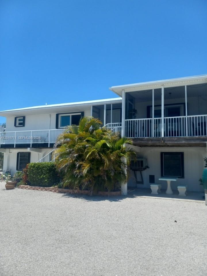 A two-story white building with a screened-in balcony and a gravel ground area — 251 Pelican Ln, Big Pine FL 33043, BIG PINE, FL