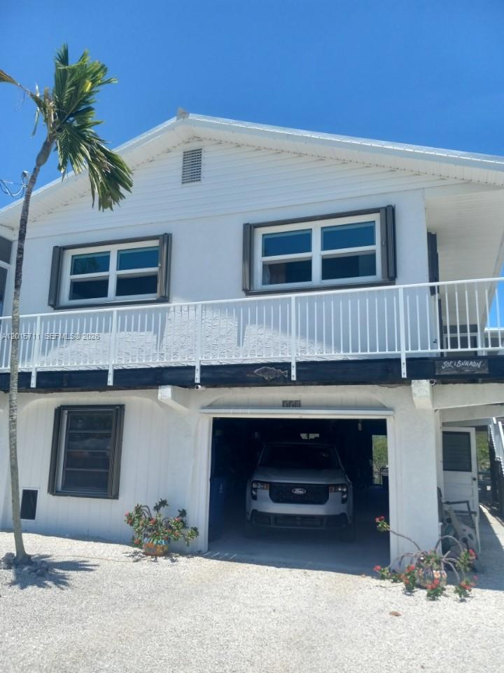 A two-story white house with a ground-level garage and a second-floor balcony — 251 Pelican Ln, Big Pine FL 33043, BIG PINE, FL