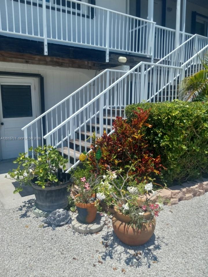 An exterior view shows a white staircase leading to a deck beside potted plants — 251 Pelican Ln, Big Pine FL 33043, BIG PINE, FL