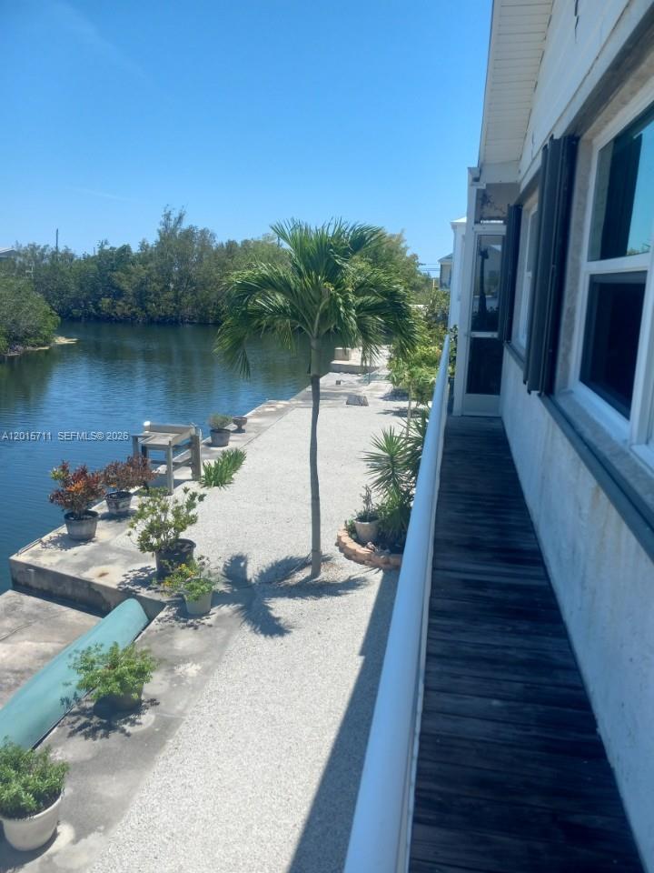 A wooden balcony overlooks a gravel patio with potted plants and a canal — 251 Pelican Ln, Big Pine FL 33043, BIG PINE, FL
