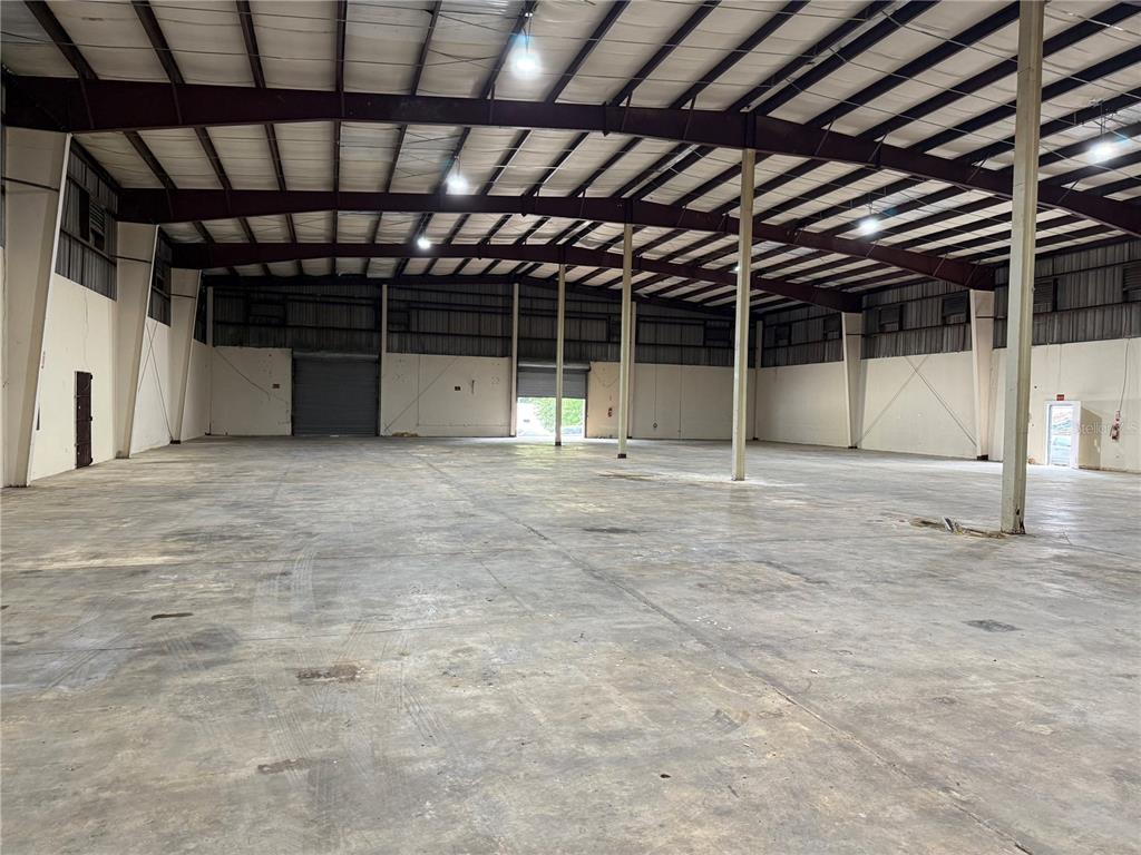 An expansive, empty warehouse interior features a concrete floor, metal support columns, and roll-up doors — Carr #2 KM 17.0, TOA BAJA, PR