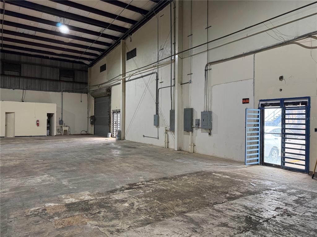 An empty industrial warehouse space features concrete floors, exposed ceiling beams, and metal doors — Carr #2 KM 17.0, TOA BAJA, PR