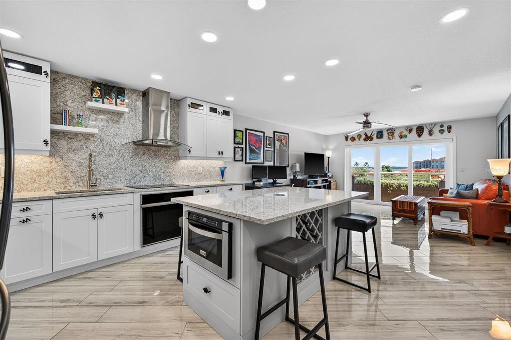 A modern kitchen with white cabinets, granite countertops, and a central island with bar seating — 4900 BRITTANY DRIVE S UNIT 409, ST PETERSBURG, FL