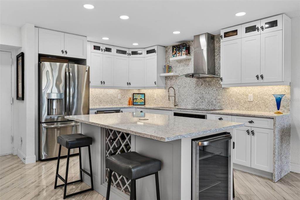 A modern kitchen features white cabinetry, a granite-topped island with seating, and stainless steel appliances — 4900 BRITTANY DRIVE S UNIT 409, ST PETERSBURG, FL