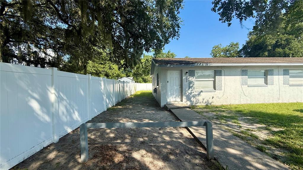 A white house exterior features a side entrance, a white vinyl fence, and a walkway — 205 MILL STREET, WILDWOOD, FL