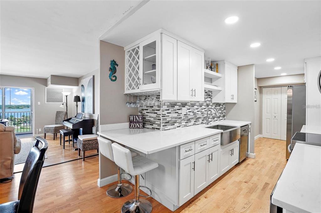 A white kitchen features a wine rack, bar seating, and a view of the water — 10355 PARADISE BOULEVARD UNIT 1010-1011, ST PETERSBURG, FL