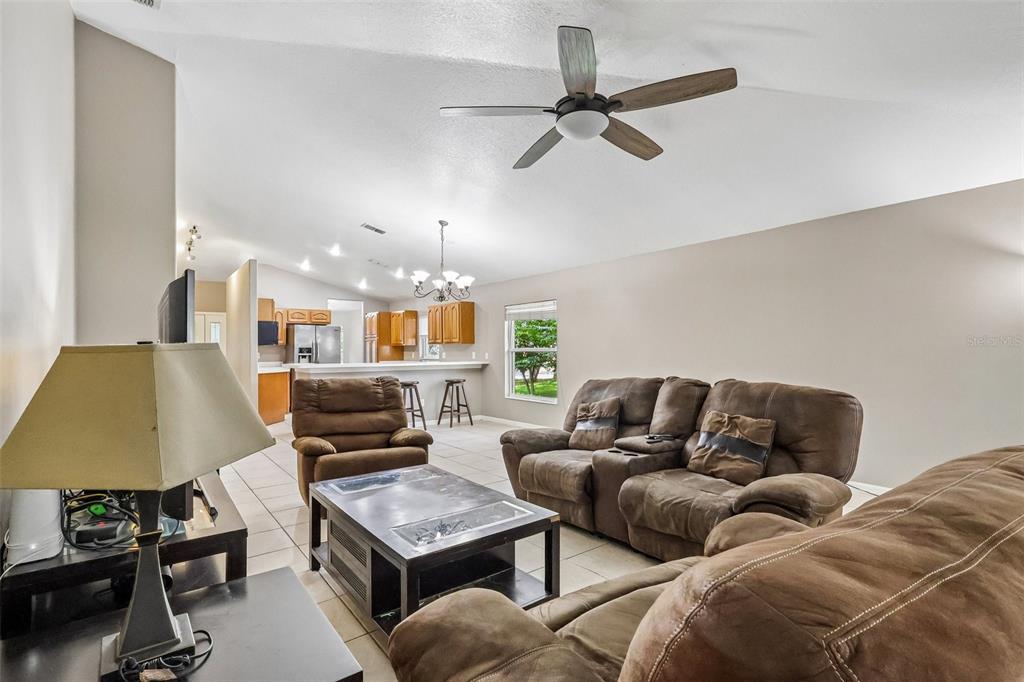 A living room with brown furniture, a ceiling fan, and an open kitchen in back — 619 CORAL WAY, WINTER SPRINGS, FL