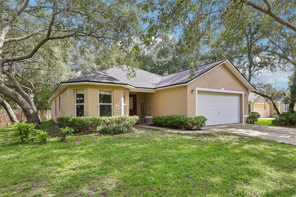A tan, single-story house with a two-car garage and a front yard with large trees — 619 CORAL WAY, WINTER SPRINGS, FL