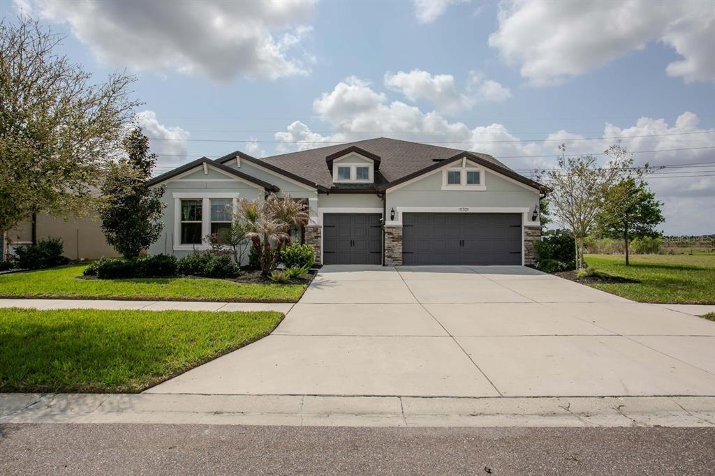 A single-story house with a three-car garage, light siding, and a concrete driveway — 11701 BRIGHTON KNOLL LOOP, RIVERVIEW, FL