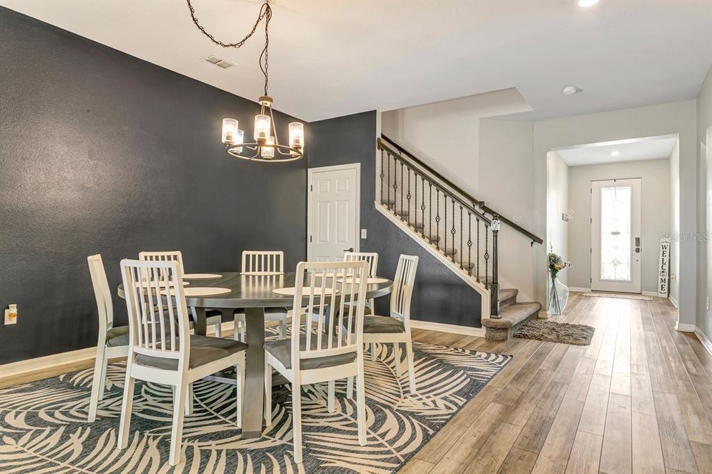 A dining room features a dark accent wall, a round table with chairs, and stairs — 11701 BRIGHTON KNOLL LOOP, RIVERVIEW, FL