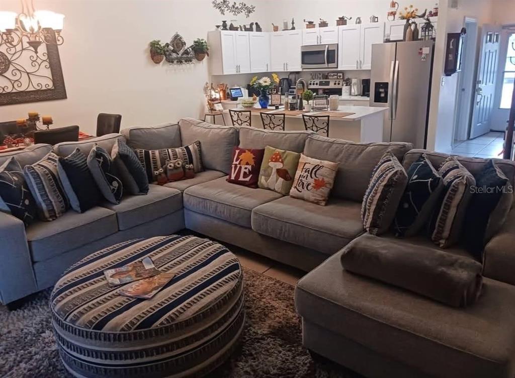 A living room with a large gray sectional sofa and ottoman facing an open kitchen — 2409 MING COURT, KISSIMMEE, FL