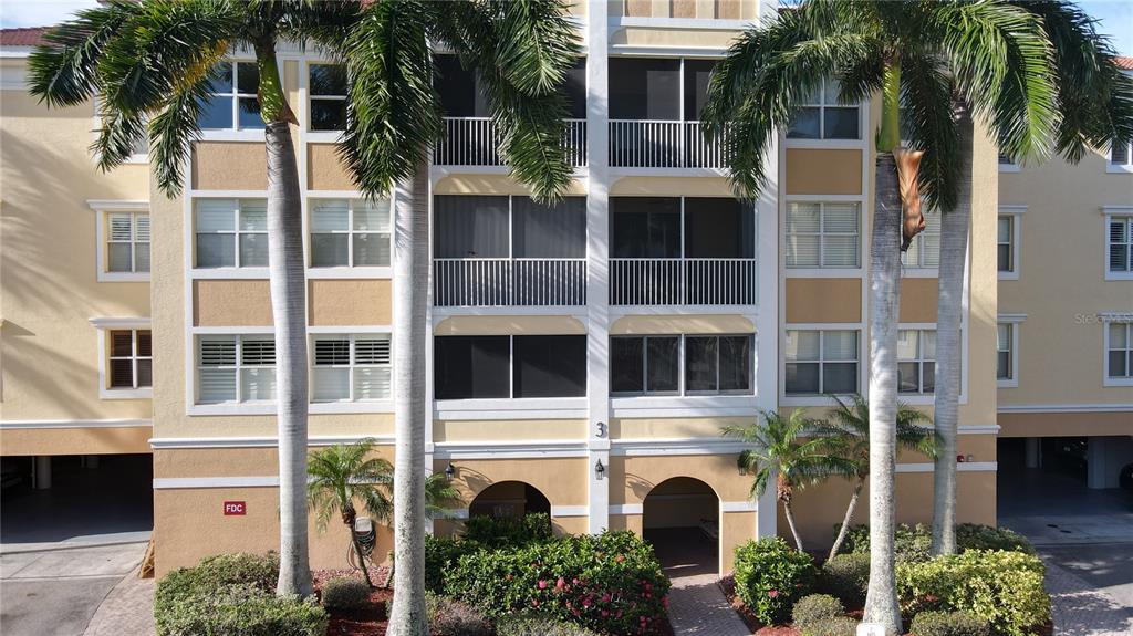 A multi-story residential building with tan stucco walls, screened balconies, and palm trees in front — 255 W END DRIVE UNIT 3206, PUNTA GORDA, FL