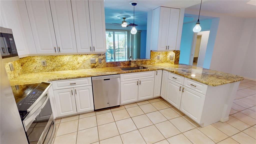 A kitchen with white cabinets, granite countertops, stainless steel appliances, and beige tile flooring — 255 W END DRIVE UNIT 3206, PUNTA GORDA, FL
