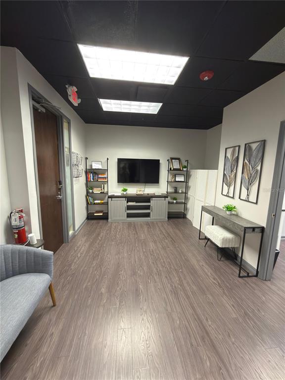 A waiting room features wood-look flooring, a television, shelving units, and a console table — 6735 CONROY ROAD UNIT 201, 203, ORLANDO, FL