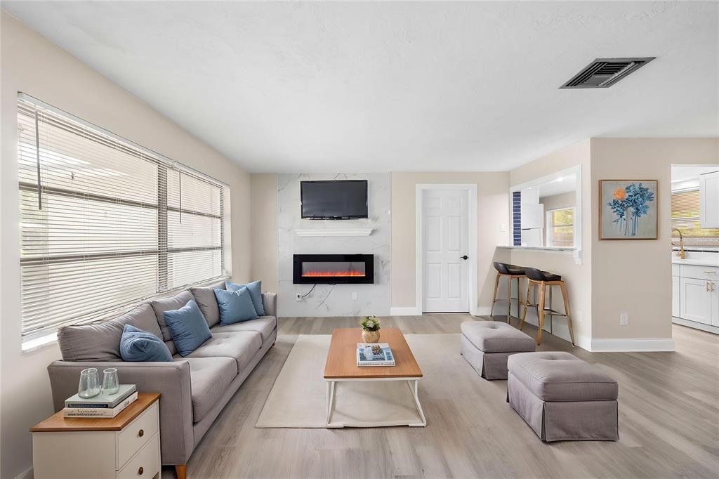 A living room features a gray sofa, a fireplace with a television, and bar seating — 1820 PATLIN CIRCLE N, LARGO, FL