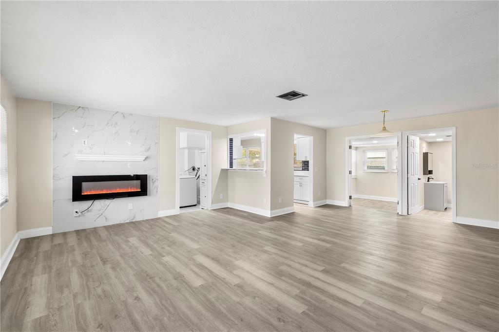 A living room features light wood-look flooring, a marble-tiled fireplace, and multiple doorways — 1820 PATLIN CIRCLE N, LARGO, FL