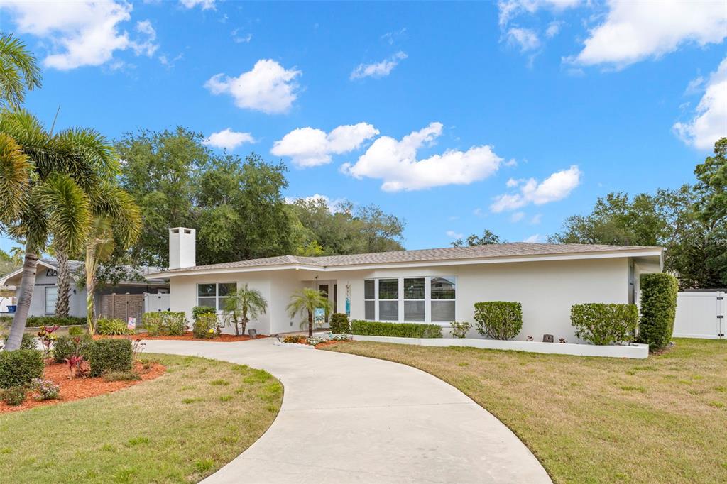 A single-story house with a white exterior, a curved driveway, and a chimney — 125 CARLYLE DRIVE, PALM HARBOR, FL