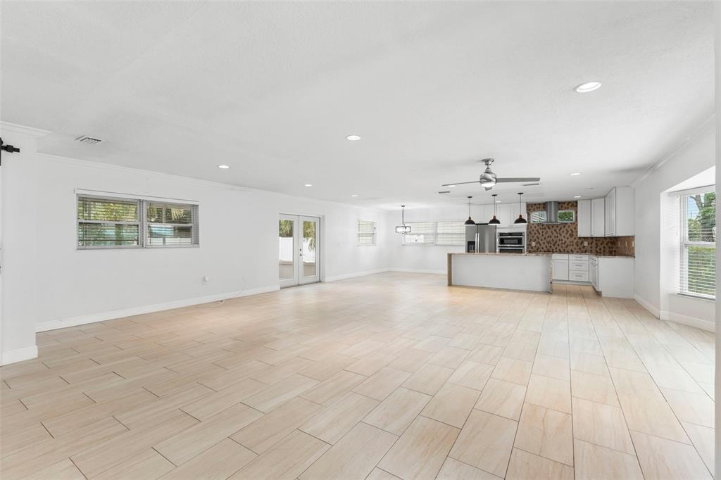 A spacious, open-concept living area features light-colored tile flooring, white walls, and a modern kitchen — 125 CARLYLE DRIVE, PALM HARBOR, FL