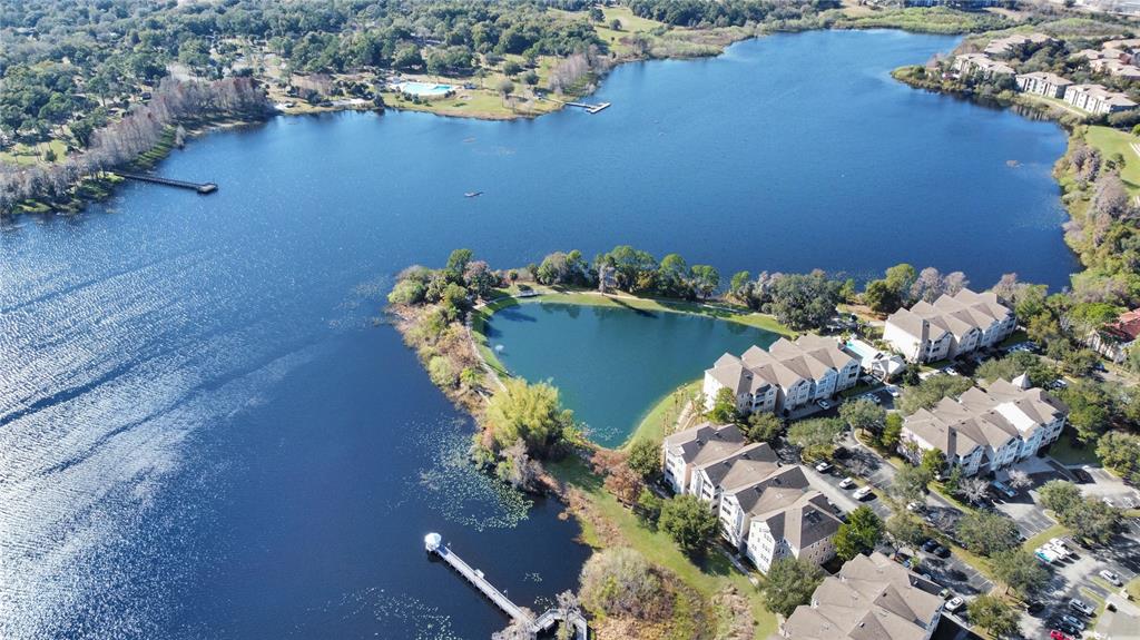 An aerial view shows apartment buildings situated on a peninsula surrounded by a large lake — 6413 ASTOR VILLAGE AVENUE UNIT 315, ORLANDO, FL