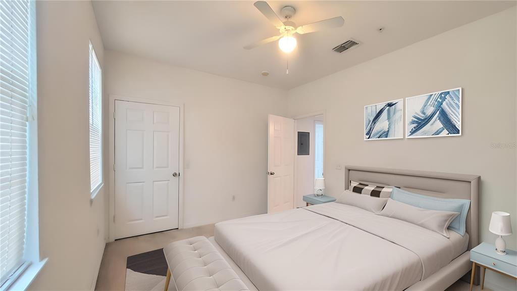 A bedroom features a bed with a tufted bench, ceiling fan, and two wall art pieces — 6413 ASTOR VILLAGE AVENUE UNIT 315, ORLANDO, FL
