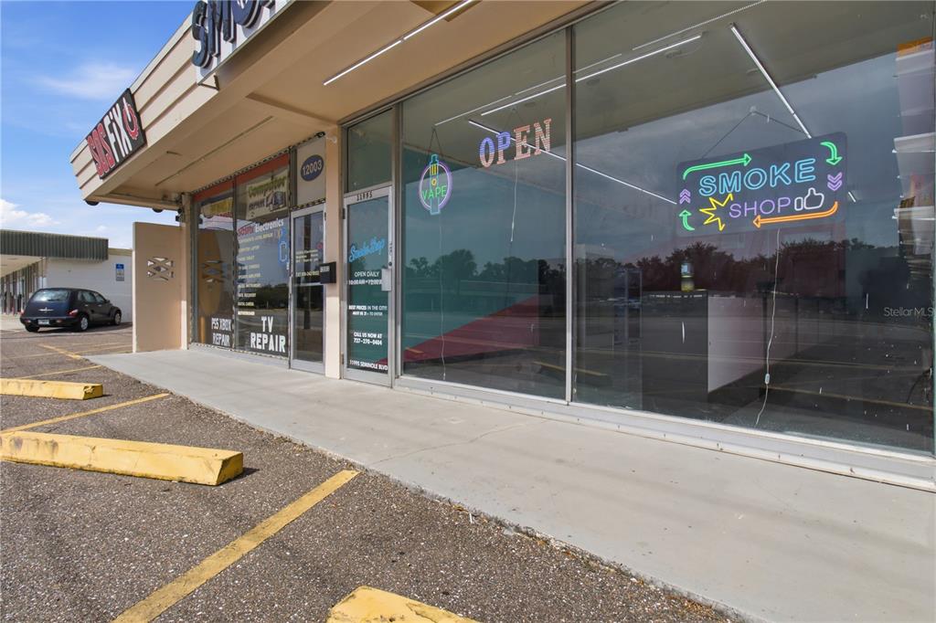 The exterior of a commercial storefront features large glass windows and a neon sign — SEMINOLE BOULEVARD, LARGO, FL