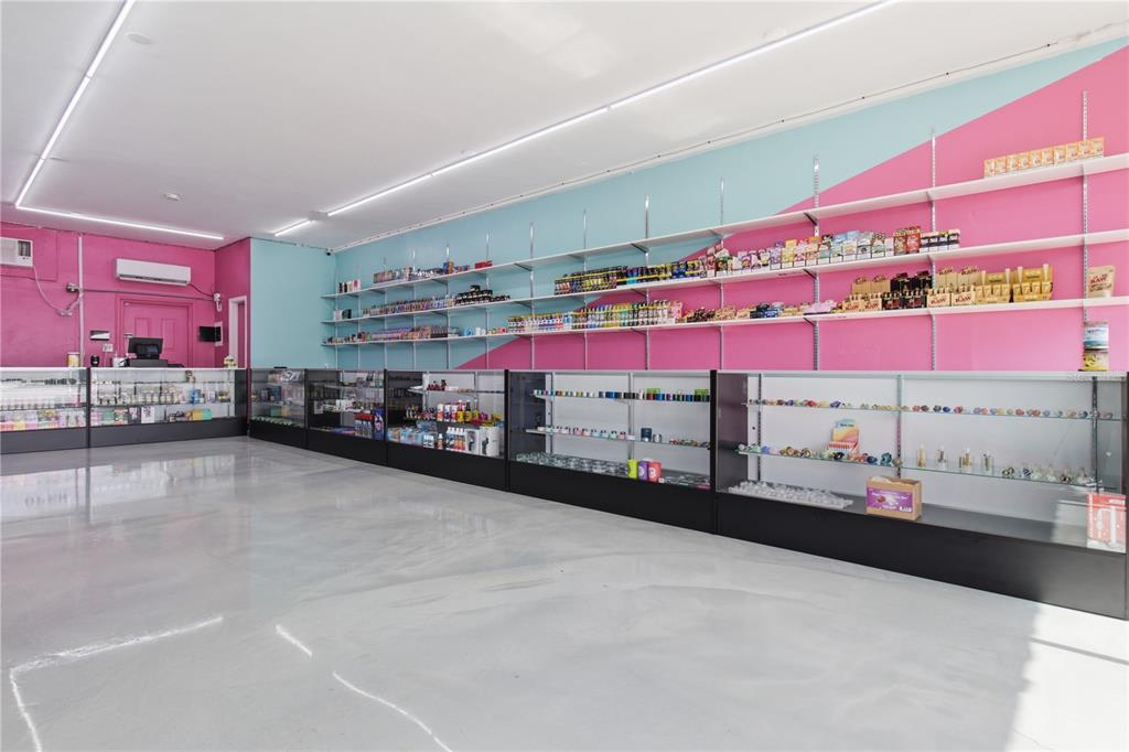 A retail shop interior features pink and blue walls, glass display cases, and white shelving — SEMINOLE BOULEVARD, LARGO, FL