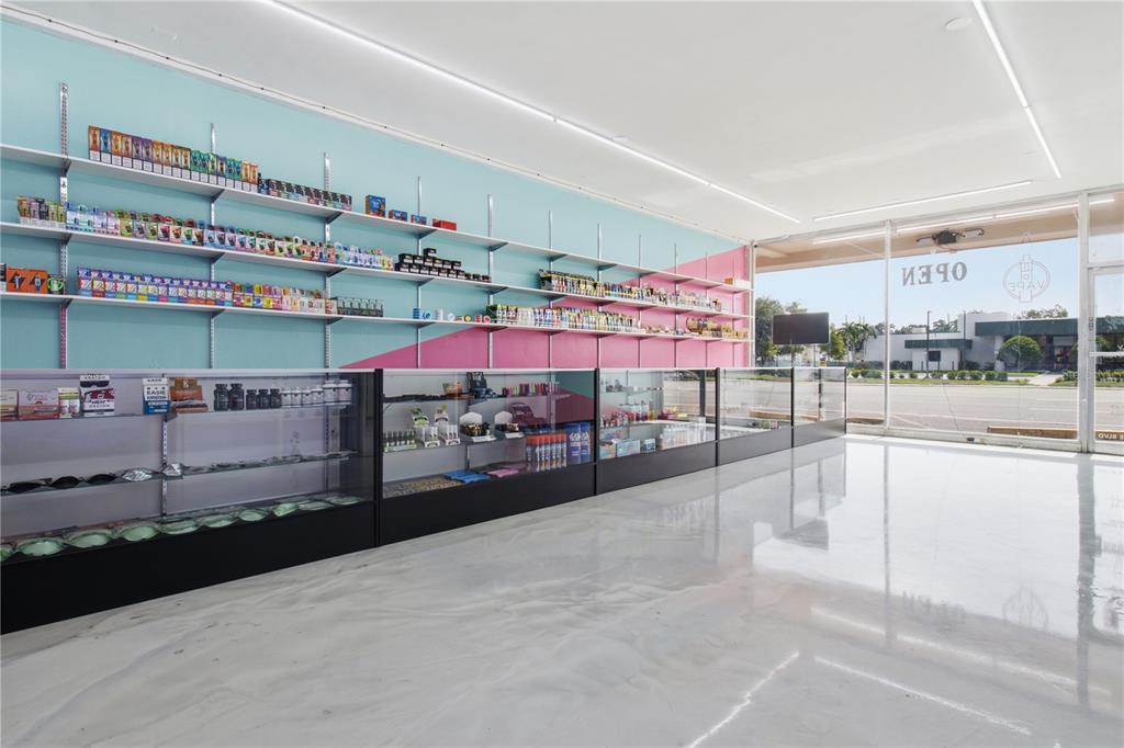 A retail vape shop interior features light blue and pink walls with extensive display shelving — SEMINOLE BOULEVARD, LARGO, FL