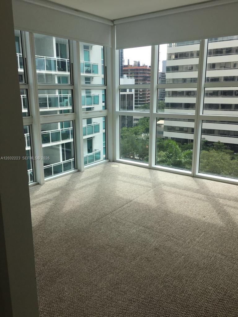 An empty room with beige carpet and floor-to-ceiling windows overlooking an urban area — 950 Brickell Bay Dr # 701, Miami FL 33131, MIAMI, FL