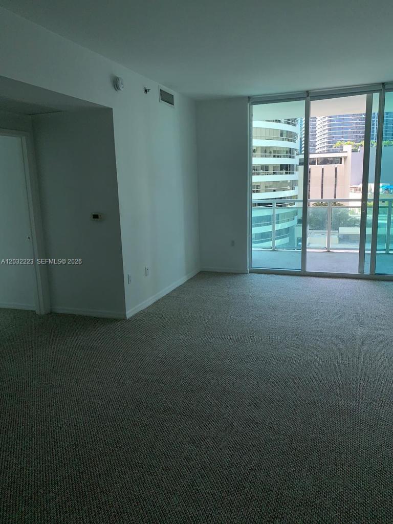 An empty room with beige carpet, white walls, and a large sliding glass door — 950 Brickell Bay Dr # 701, Miami FL 33131, MIAMI, FL