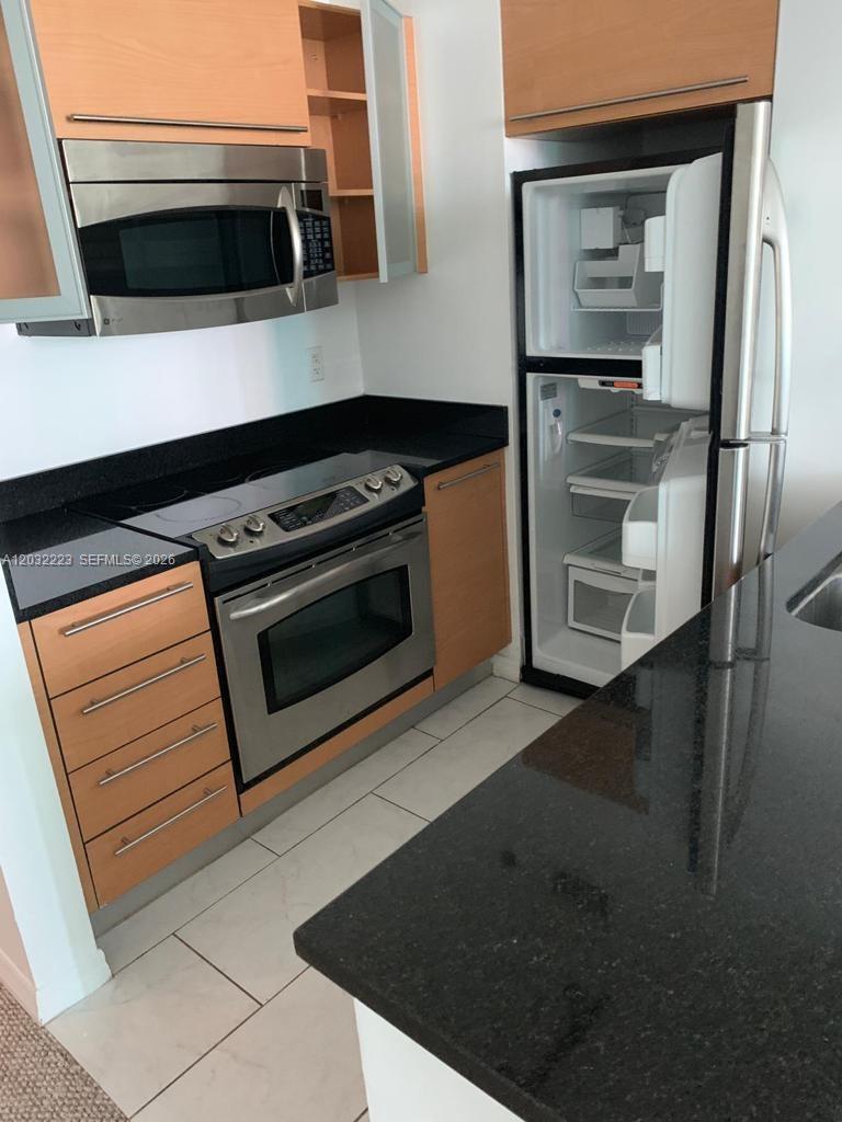 A kitchen features light wood cabinets, stainless steel appliances, and black granite countertops — 950 Brickell Bay Dr # 701, Miami FL 33131, MIAMI, FL