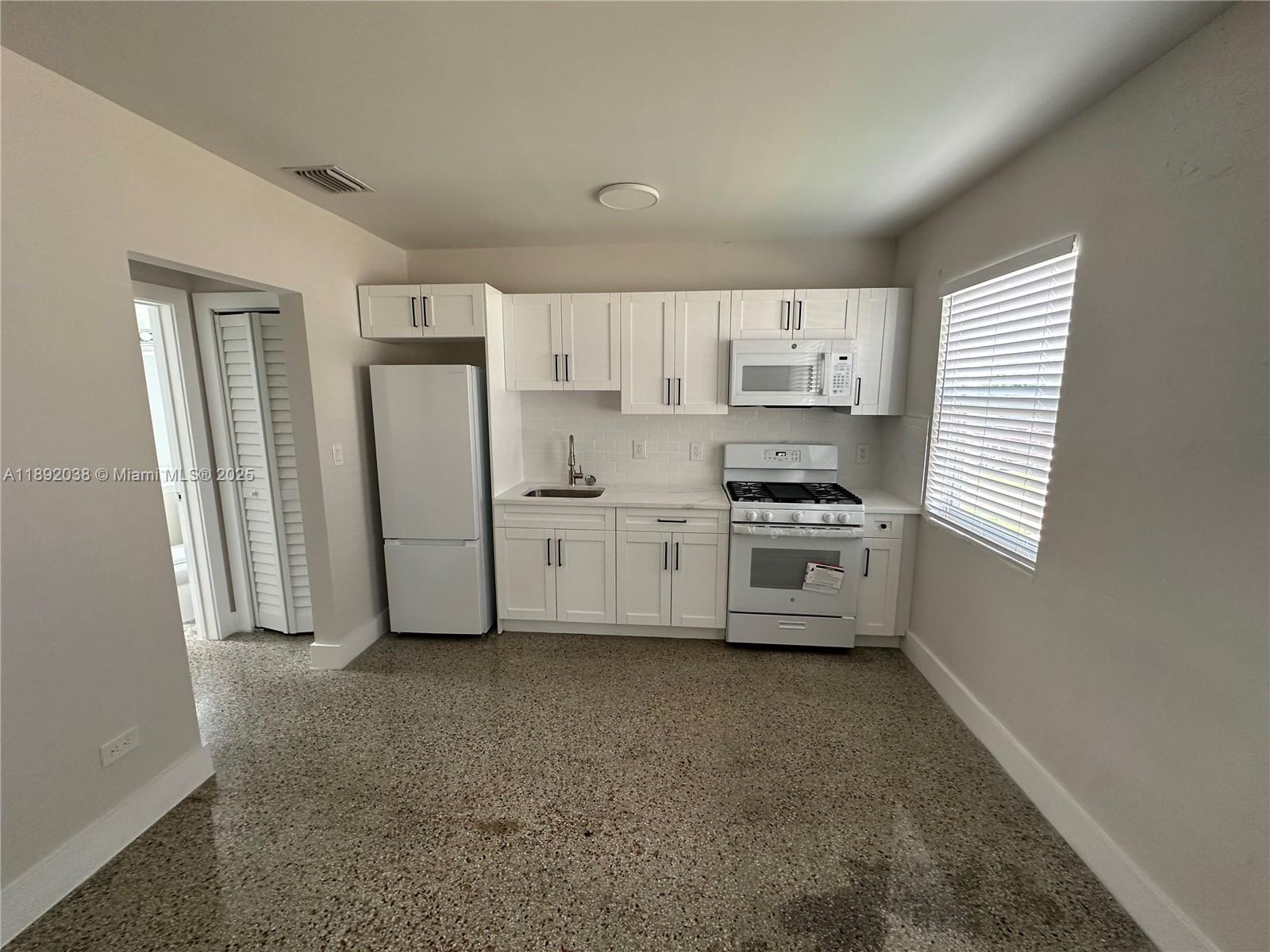 A kitchen features white cabinets, white appliances, a sink, and a speckled floor — 211 SW 18th Ave # 2, Miami FL 33135, MIAMI, FL