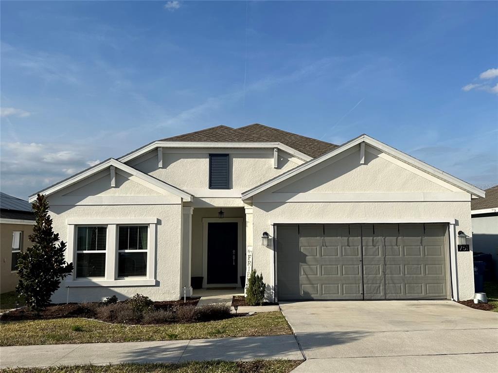 A single-story house with a white stucco exterior, a two-car garage, and a front entrance — 751 STAFFORA STREET, HAINES CITY, FL