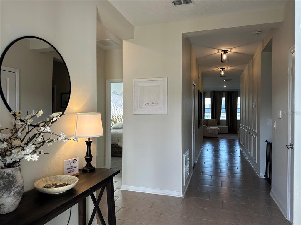 A hallway with tile flooring leads to a living area with large windows and pendant lighting — 751 STAFFORA STREET, HAINES CITY, FL