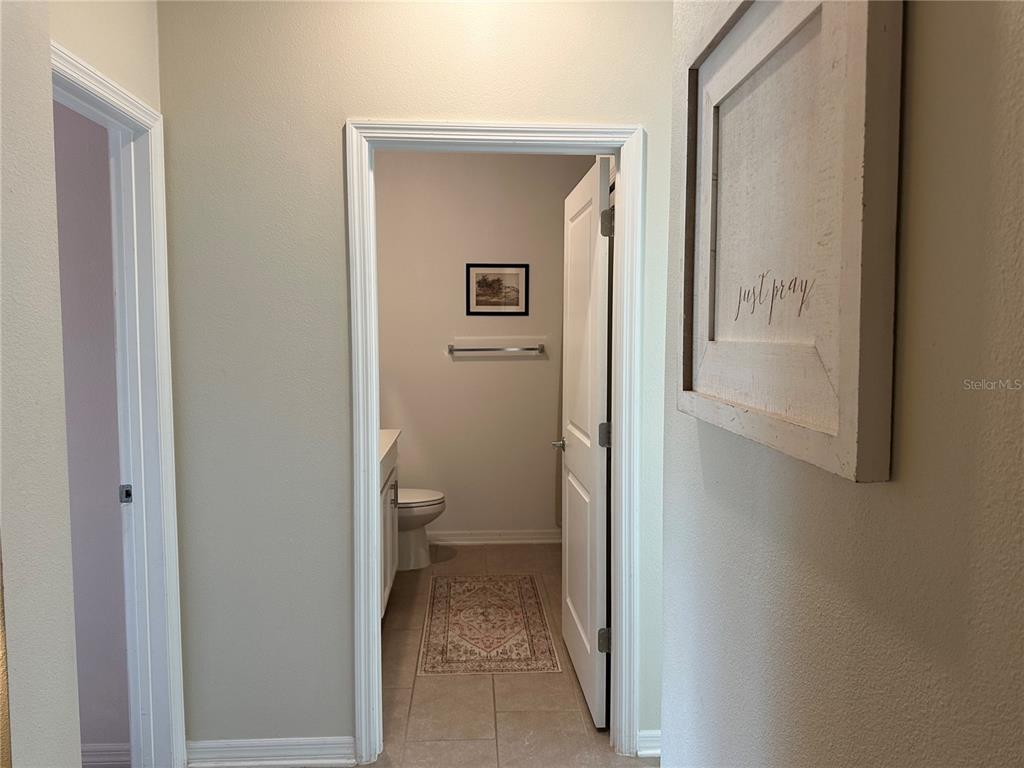 A hallway leads to a bathroom with a toilet, vanity, and framed wall art — 751 STAFFORA STREET, HAINES CITY, FL