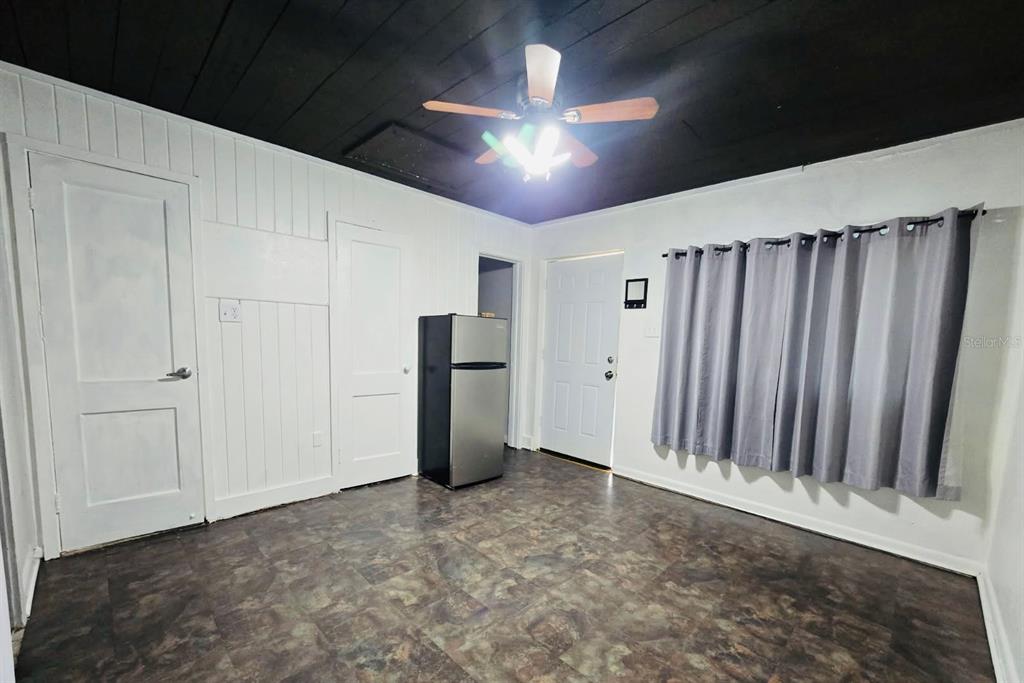 A room with white paneled walls, a black ceiling, a ceiling fan, and a refrigerator — 8010 SE US HIGHWAY 301 UNIT 2A, HAWTHORNE, FL