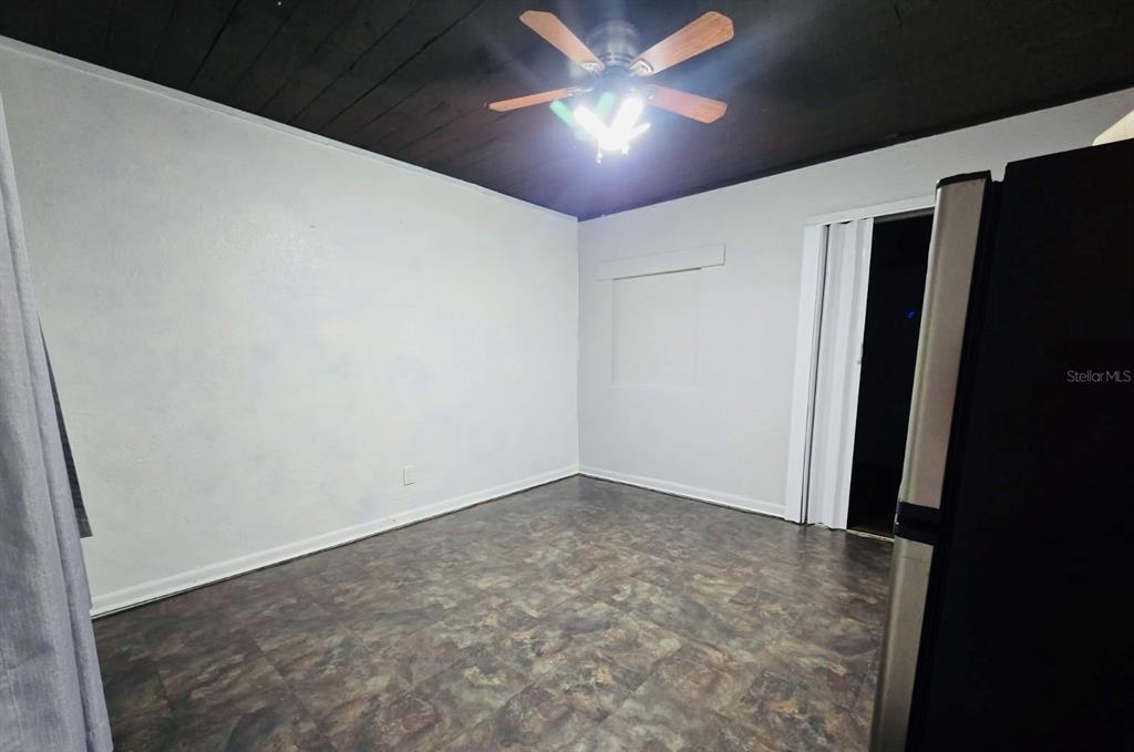 An empty room features white walls, a dark wood-paneled ceiling, and patterned vinyl flooring — 8010 SE US HIGHWAY 301 UNIT 2A, HAWTHORNE, FL