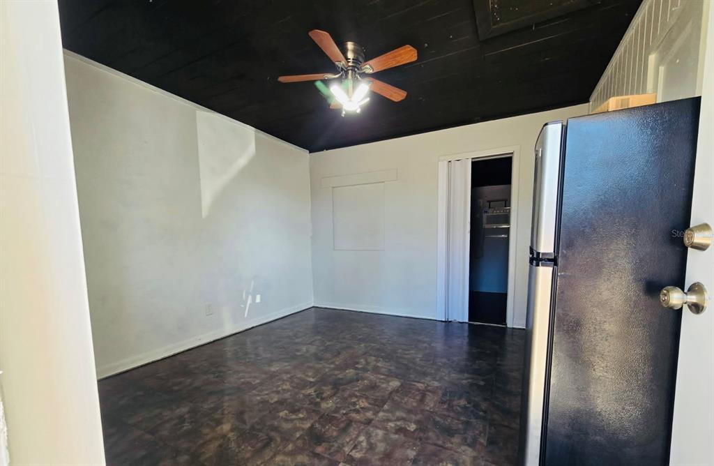 A room with dark ceiling, ceiling fan, white walls, and dark patterned flooring — 8010 SE US HIGHWAY 301 UNIT 2A, HAWTHORNE, FL