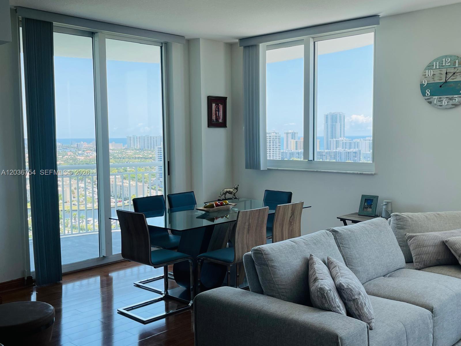 A dining area with a glass table and city views through floor-to-ceiling windows — HALLANDALE BEACH, FL