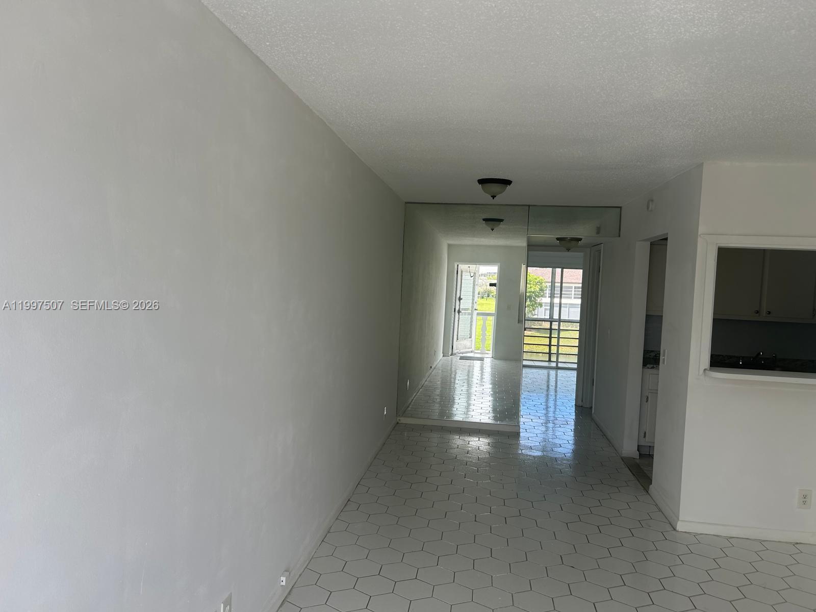 A room with white hexagonal floor tiles, a mirrored wall, and a view of outdoors — 89 Berkshire D # 89, West Palm Beach FL 33417, WEST PALM BEACH, FL