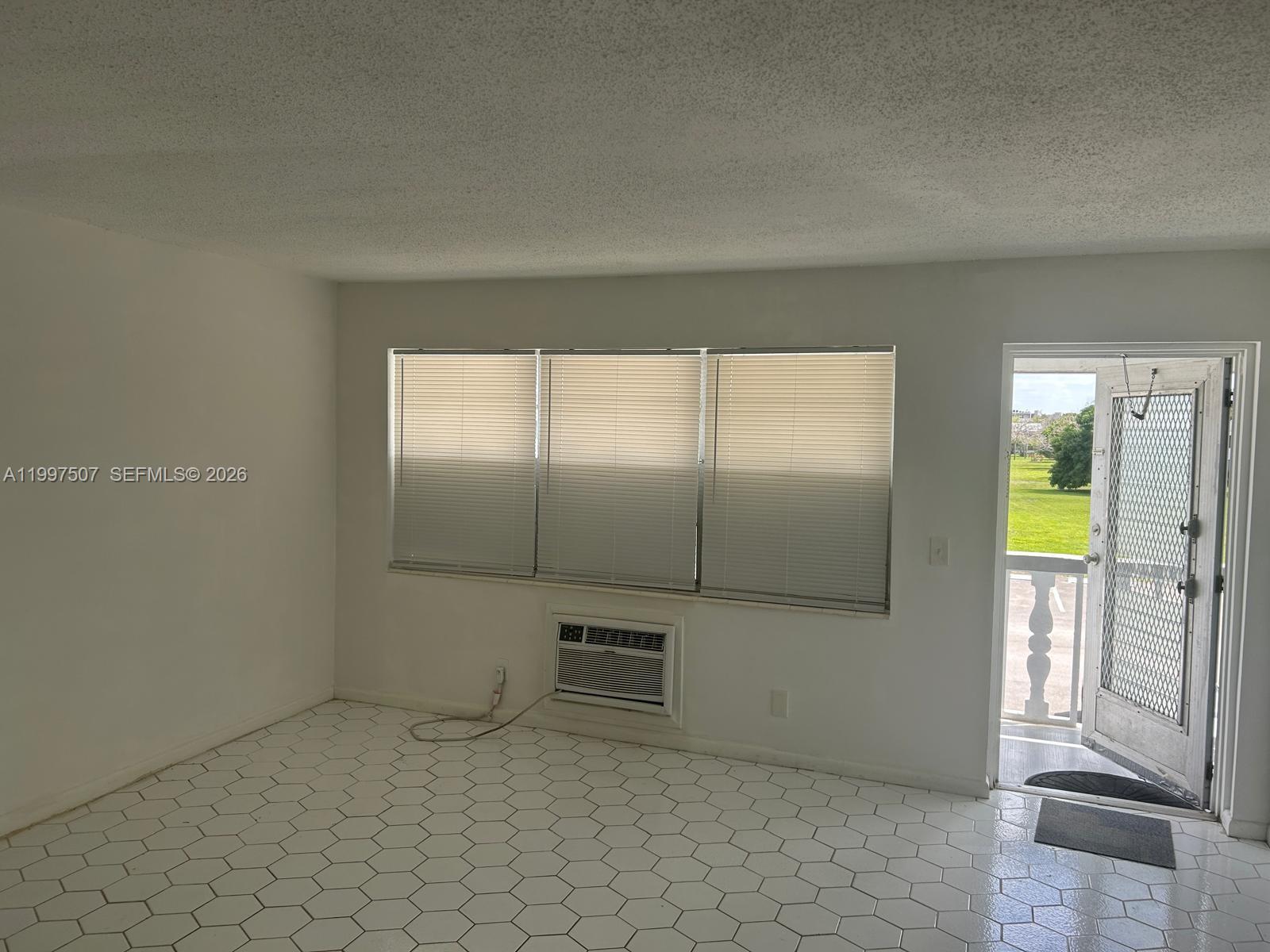 A room with white hexagonal floor tiles, a window air conditioner, and an open door — 89 Berkshire D # 89, West Palm Beach FL 33417, WEST PALM BEACH, FL
