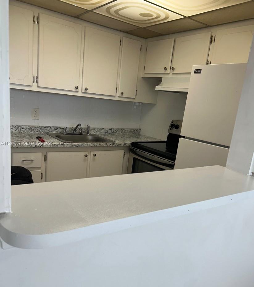 A kitchen features white cabinets, a granite-look countertop, a stainless steel sink, and appliances — 89 Berkshire D # 89, West Palm Beach FL 33417, WEST PALM BEACH, FL