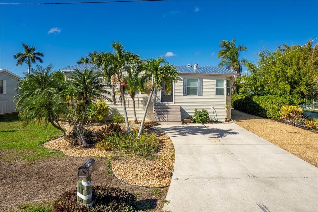 A single-story house with light siding, a metal roof, and a concrete driveway — 3101 BAMBOO COURT, PUNTA GORDA, FL