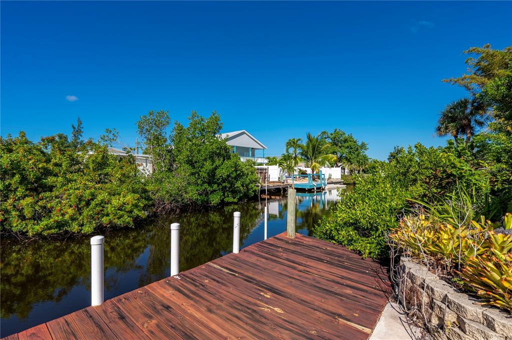 A wooden dock overlooks a narrow canal lined with lush green mangroves and palm trees — 3101 BAMBOO COURT, PUNTA GORDA, FL