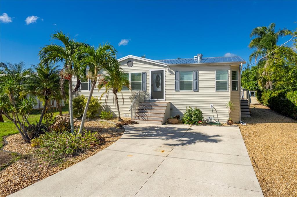A single-story mobile home with light siding, a metal roof, and a concrete driveway — 3101 BAMBOO COURT, PUNTA GORDA, FL