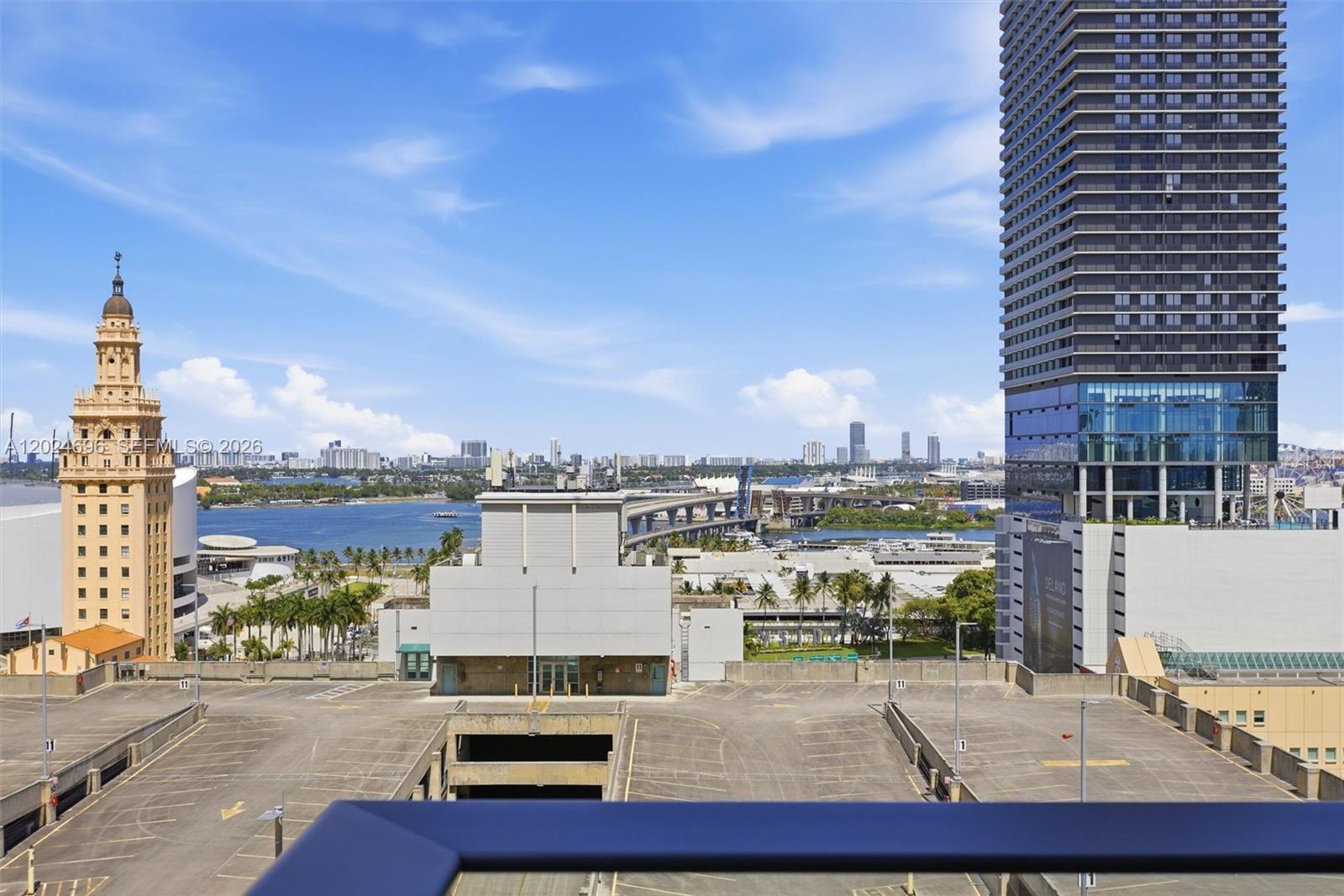 An elevated view shows a parking garage rooftop overlooking a bay, a bridge, and city skyscrapers — 121 NE 5th St # 1712, Miami FL 33132, MIAMI, FL