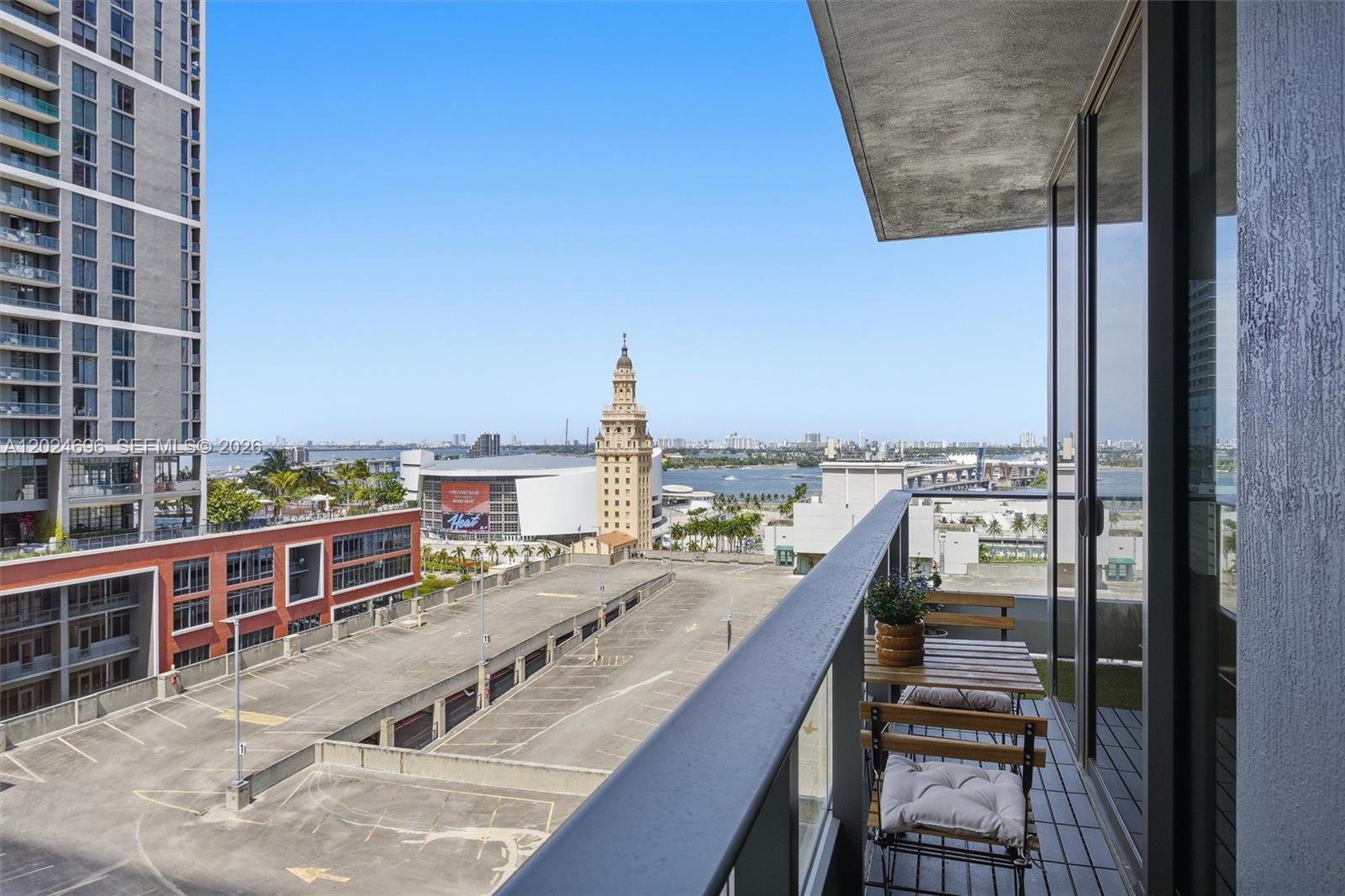 A balcony with a small table and chairs overlooks a parking lot and city skyline — 121 NE 5th St # 1712, Miami FL 33132, MIAMI, FL