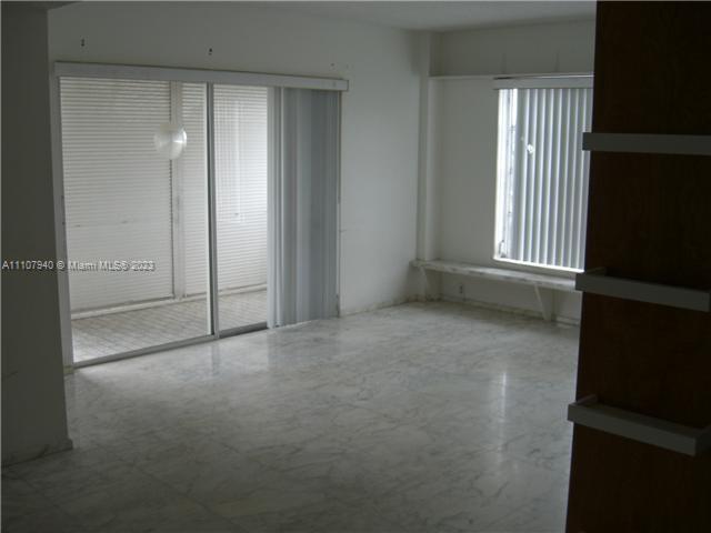 An empty room with marble floors, a sliding glass door, and a window with vertical blinds — 4158 Inverrary Dr # 411, Lauderhill FL 33319, LAUDERHILL, FL