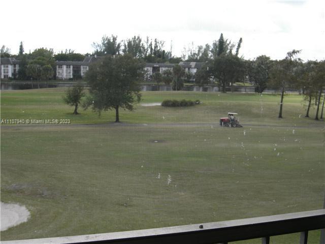 A view from a balcony overlooking a golf course with a maintenance vehicle — 4158 Inverrary Dr # 411, Lauderhill FL 33319, LAUDERHILL, FL