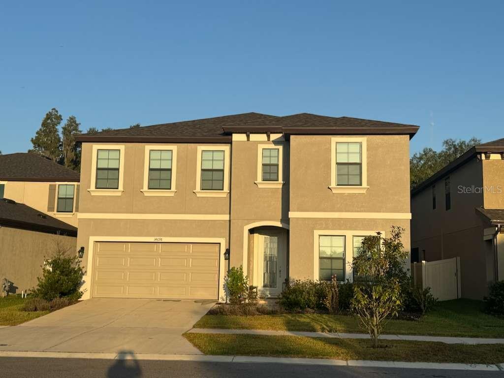 A two-story suburban house with a beige stucco exterior, a two-car garage, and a driveway — 14698 HORSE TROT ROAD, LITHIA, FL