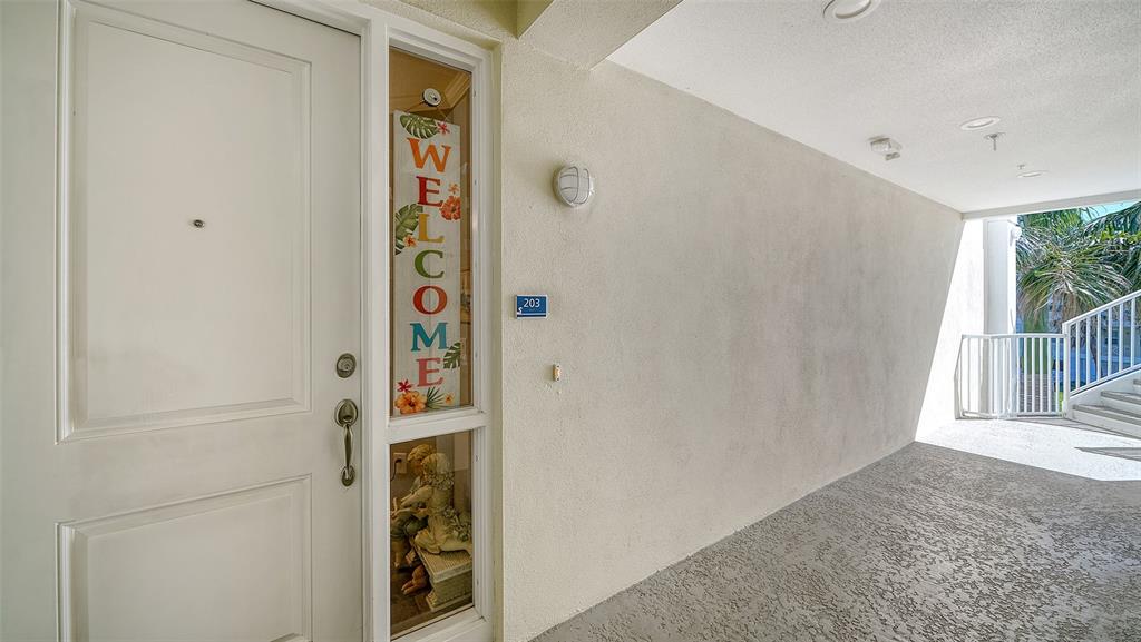 An exterior view of a white apartment door with a welcome sign and unit number 203 — 7910 34TH AVENUE W UNIT 203, BRADENTON, FL